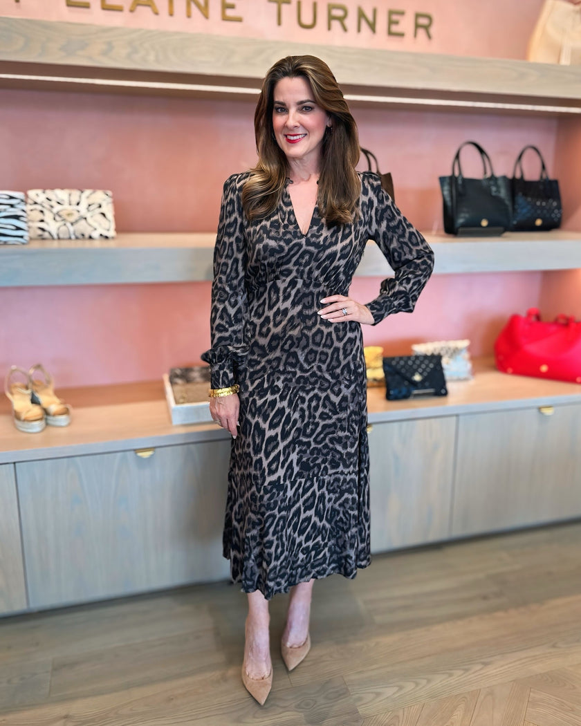 Elaine in a leopard print Dea Kudibal midi length dress standing in front of a display of handbags at edit. BY ELAINE TURNER