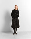 A model stands against a light gray studio background wearing a black long-sleeve knit sweater with tonal floral embroidery and a matching black textured midi skirt.

Beatrice B- crew neck sweater with embroidered appliques. Available at Edit by Elaine Turner in Houston, TX. Model full front view. 