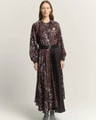 A woman models a long-sleeved midi dress with a burnt amber abstract print, featuring a tie-neck detail, a matching black belt, and a pleated skirt, set against a plain light gray background.

Beatrice B Printed Silk Midi Dress with Pleats. Available at Edit by Elaine Turner in Houston, TX. Full front model view. 