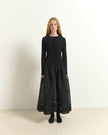 A woman stands facing forward in a studio wearing a long-sleeve black knit top with a gathered waist and a full black skirt, paired with black shoes.

Beatrice B. Ribbed Knit Dress with Jacquard Skirt in black. Available at Edit by Elaine Turner in Houston, TX. Full Model Front View. 