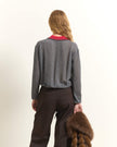 A woman shown from behind wearing a gray textured knit cardigan over a red collared shirt, paired with dark brown trousers, holding a brown fur accessory against a plain off-white background.

Beatrice B wool, silk and cashmere polo sweater in cloud gray. Available at Edit by Elaine Turner in Houston, TX. Back Model View. 