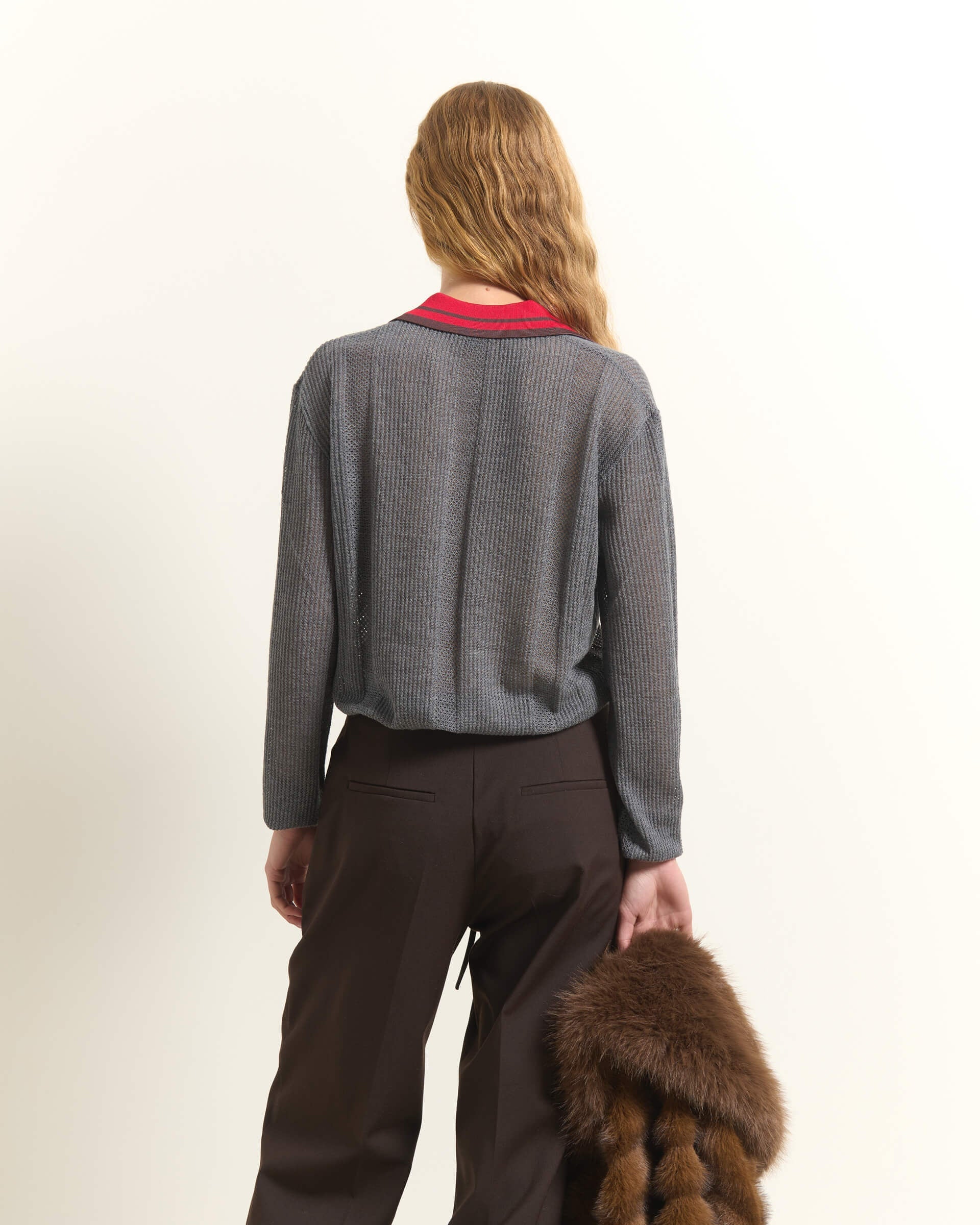 A woman shown from behind wearing a gray textured knit cardigan over a red collared shirt, paired with dark brown trousers, holding a brown fur accessory against a plain off-white background.

Beatrice B wool, silk and cashmere polo sweater in cloud gray. Available at Edit by Elaine Turner in Houston, TX. Back Model View. 