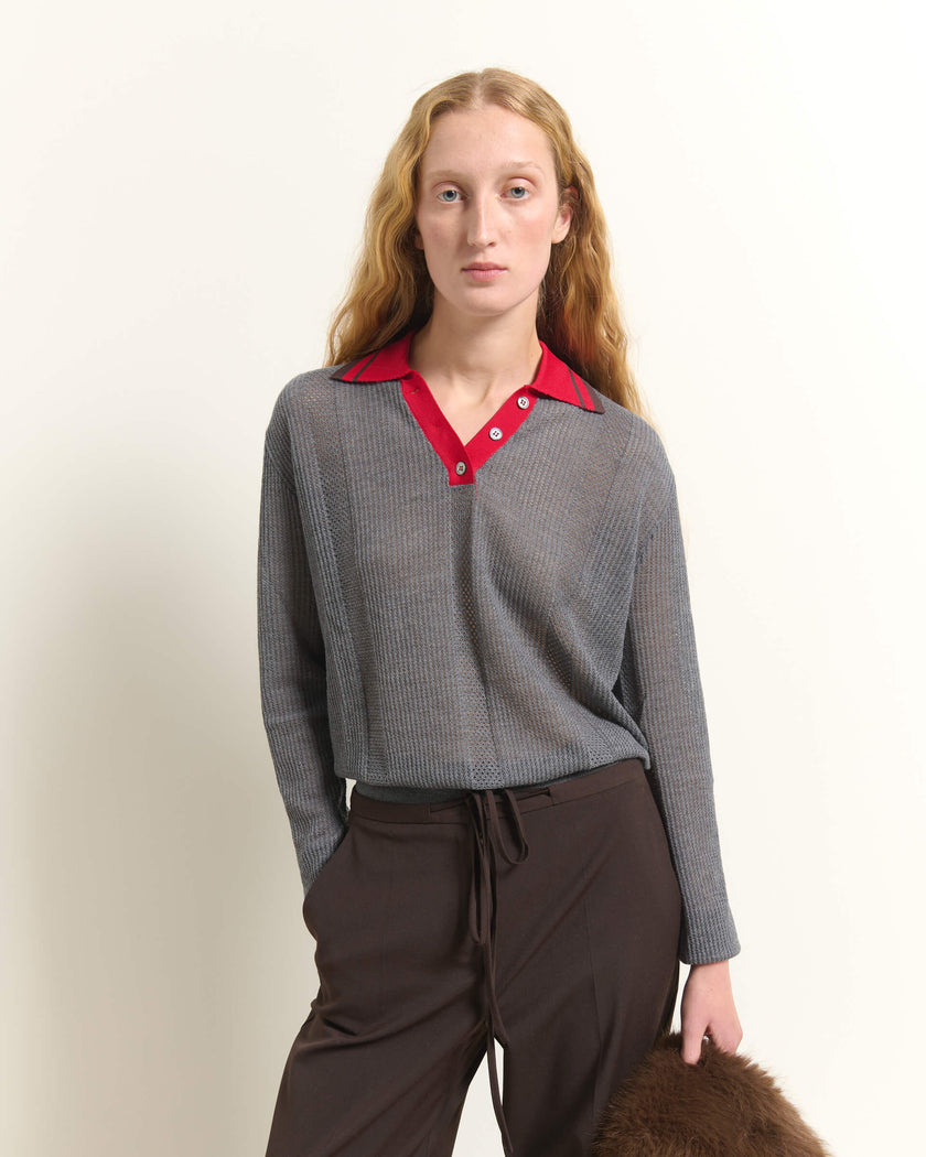 A woman modeling a gray textured knit polo shirt with a red collar, paired with dark brown drawstring trousers, against a plain off-white background.

Beatrice B wool, silk and cashmere polo sweater in cloud gray. Available at Edit by Elaine Turner in Houston, TX. Front Model View. 
