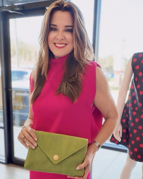 Elaine in a pink dress holding a green ET Bella clutch at edit. BY ELAINE TURNER
