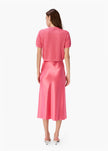 Pink skirt with floral patterns worn by a person on a white background by CAMINYC-Florina Midi Skirt in Hibiscus at edit. BY ELAINE TURNER Model is showing the back of the skirt. 
