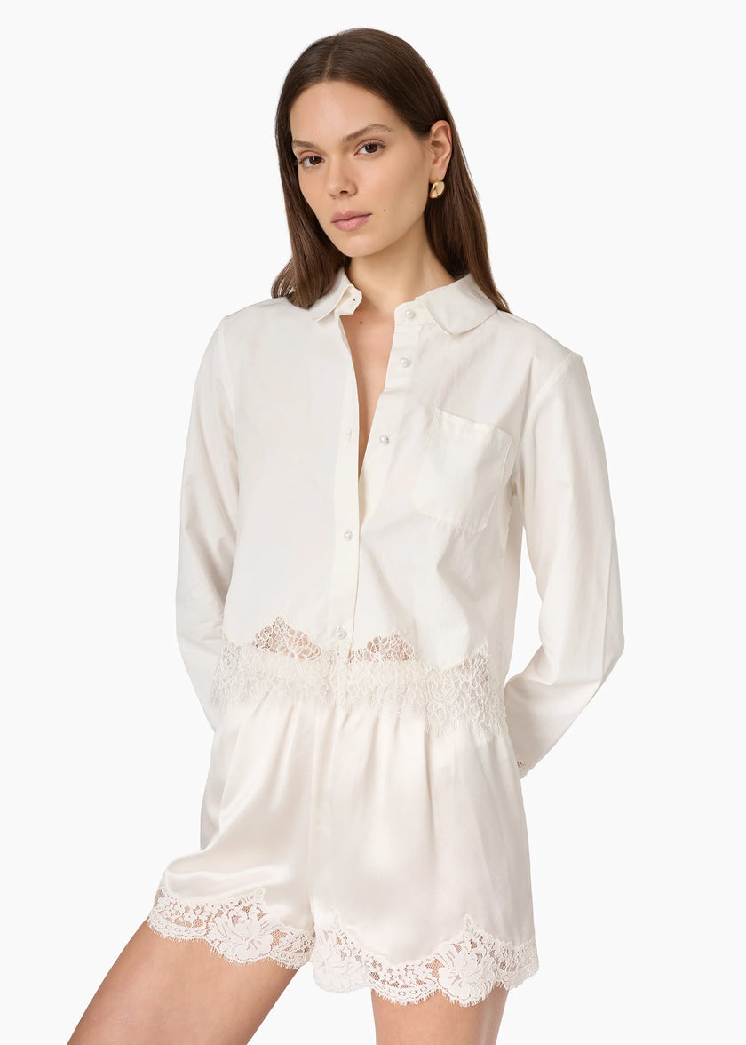A woman modeling a white long-sleeve collared shirt with matching white shorts featuring delicate lace trim at the waist and hem, set against a plain white studio background.

CAMI NYC Napier Shirt in white. Available at Edit by Elaine Turner in Houston, TX. Full front model close up view. 