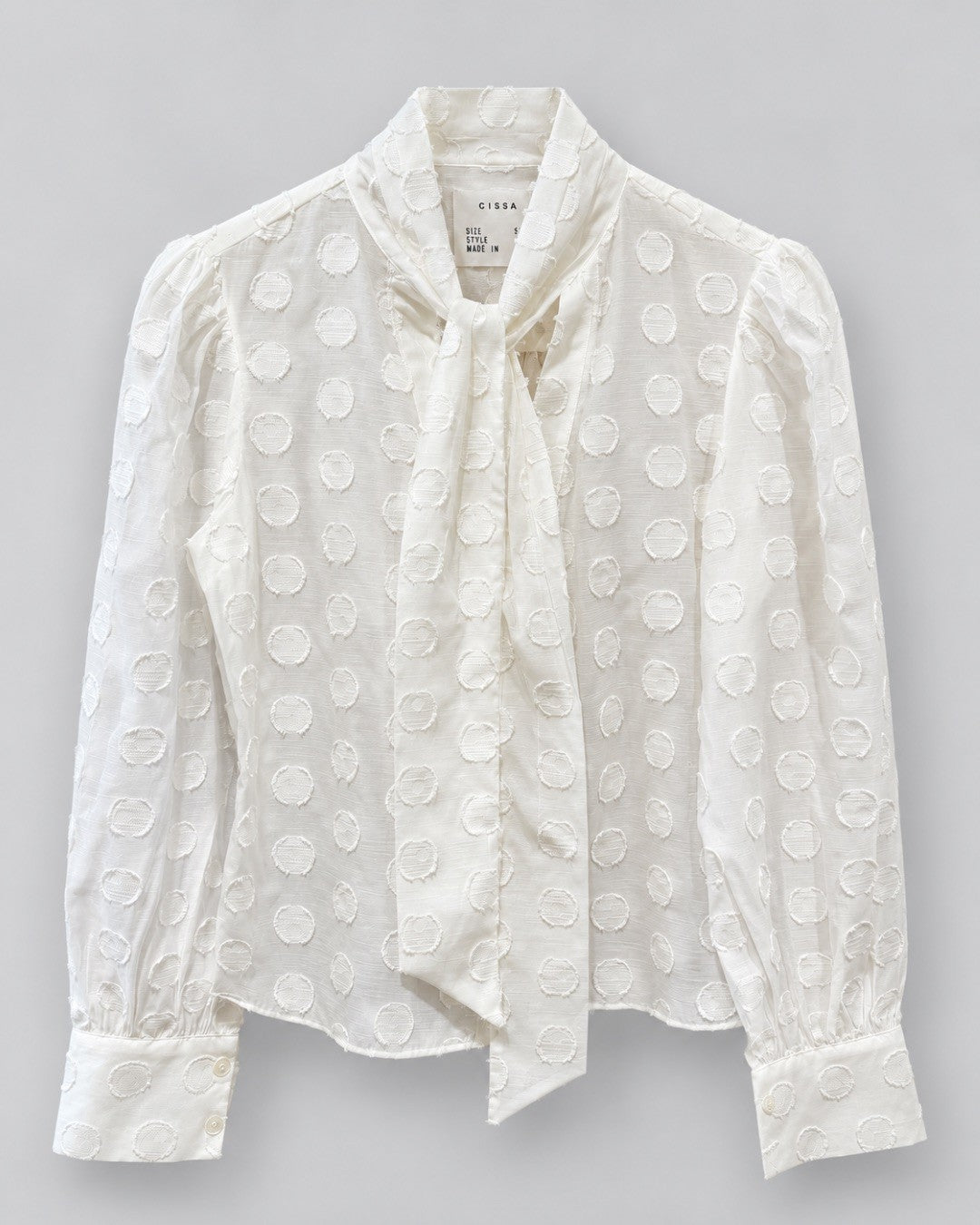 CISSA- The Bow Tie Blouse in sheer polka dot. Available at Edit by Elaine Turner in Houston, TX. Front flat lay view. 