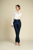 A woman modeling a white satin button-down shirt tucked into high-waisted navy trousers, standing against a solid beige studio background.

Daniel Gonzalez Marina Blouse in Foam. Available at Edit by Elaine Turner in Houston, TX. Front Model View. 