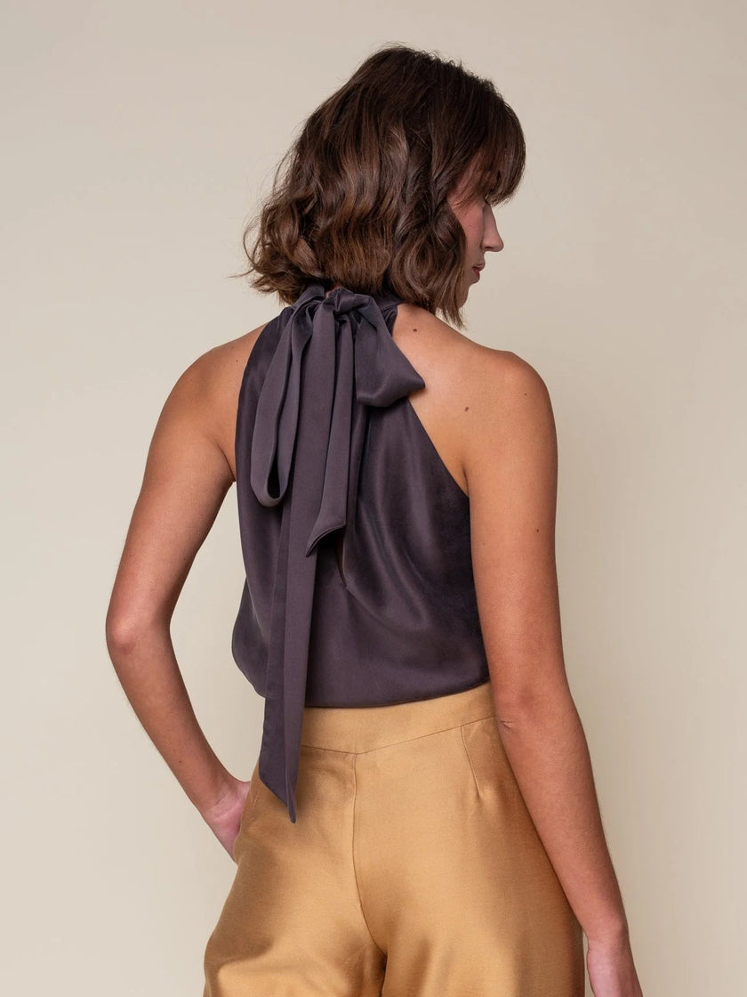A woman shown from the back wearing a dark plum halter top with a large bow detail at the back of the neck, paired with tan trousers, against a plain beige background.

Daniel Gonzalez Sabrina Blouse in Octopus Print. Available at Edit by Elaine Turner in Houston, TX. Back Model View. 

The Octopus Print will have this exact style in the back, but not the color in this particular picture. 