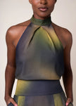 A close-up of a model wearing a textured halter-neck top with a gradient color transition from olive green to dark slate gray.

Daniel Gonzalez Sabrina Blouse in Octopus Print. Available at Edit by Elaine Turner in Houston, TX. Close Up Model View. 