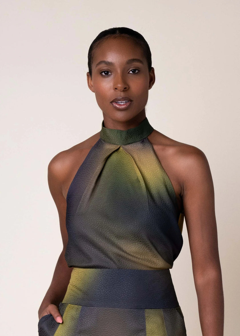 A model wearing a sleeveless halter-neck blouse with a textured, tonal gradient pattern in olive green, yellow, and dark gray, set against a plain beige studio background.

Daniel Gonzalez Sabrina Blouse in Octopus Print. Available at Edit by Elaine Turner in Houston, TX. Front Model View. 