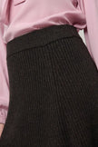 Close-up of a dark charcoal ribbed knit skirt paired with a light pink satin 
blouse.

Dea Kudibal- Alesandra knit skirt dusty chocolate. Available at Edit by Elaine Turner in Houston, TX. Close Up View. 