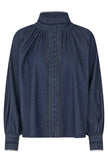 A dark blue denim long-sleeve blouse with a high gathered mock neck, decorative button placket, and embroidered sleeve details, shown on a plain white background.

Dea Kudibal Monia Blouse Chambray Blue. Available at Edit by Elaine Turner in Houston, TX . Flat Lay View. 