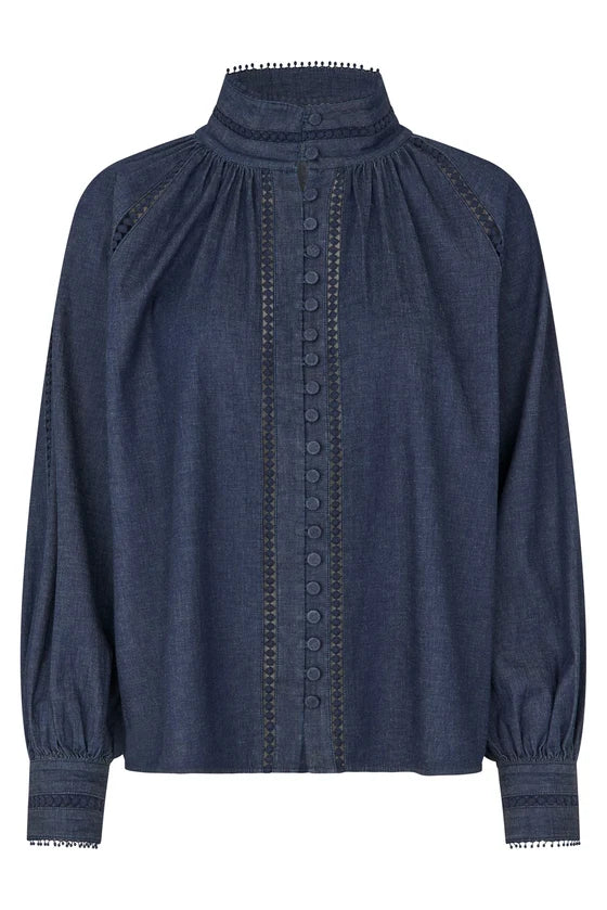 A dark blue denim long-sleeve blouse with a high gathered mock neck, decorative button placket, and embroidered sleeve details, shown on a plain white background.

Dea Kudibal Monia Blouse Chambray Blue. Available at Edit by Elaine Turner in Houston, TX . Flat Lay View. 