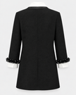 Black blazer with structured shoulders, a notched collar, and decorative black beaded ruffle trim at the cuffs, shown from the back on a white mannequin against a light gray background.

Edward Achour Extended Length Shift Dress with Contrast Bib in Black. Available at Edit by Elaine Turner in Houston, TX. Back flat lay view. 