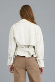A woman shown from the back wearing a cropped off-white trench jacket with a matching waist belt and tan pants, set against a solid gray studio background.

JAKETT- Naomi Vintage Leather Jacket in Coconut. Available at Edit by Elaine Turner in Houston, TX. Back model view. 
