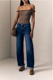 A model wearing a brown off-the-shoulder top, wide-leg blue jeans, and brown suede loafers, holding a small brown handbag against a minimalist beige background.

Le Jean- Baby Bootcut - Diamond In The Rough. Available at Edit by Elaine Turner in Houston, TX. Front Model View. 