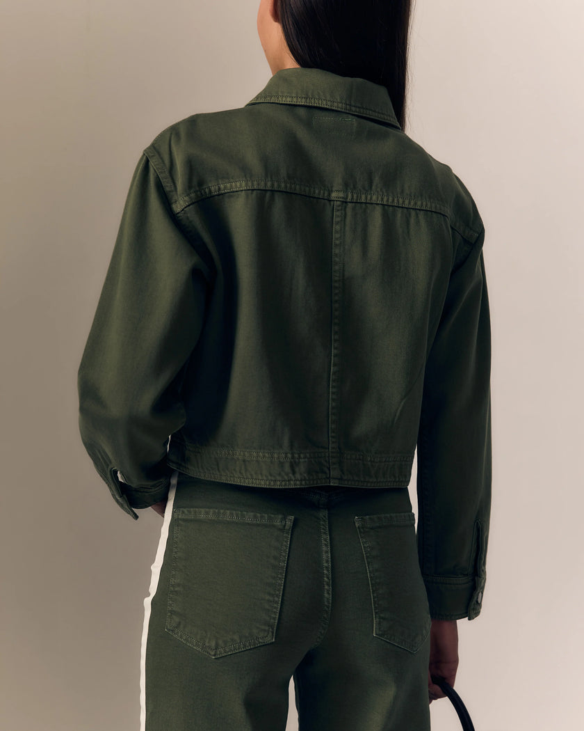Person wearing a green jacket and pants against a neutral background. 

Le Jean Cora Jacket in olive green. Available at Edit by Elaine Turner in Houston, TX. Model Back Close-Up View.