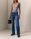 A model wearing a pair of high-waisted, straight-leg blue jeans paired with a light gray ribbed tank top and brown suede loafers, holding a dark patterned handbag in a minimalist studio setting.

Le Jean Mid 90's Straight in North Star. Available at Edit by Elaine Turner in Houston, TX. Full model front view. 