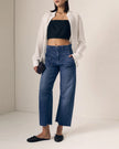 Person wearing a black crop top, blue jeans, and a white shirt against a plain background. 

Le Jean Utility Soft Barrel in London Calling. Available at Edit by Elaine Turner in Houston, TX. Full model front view. 