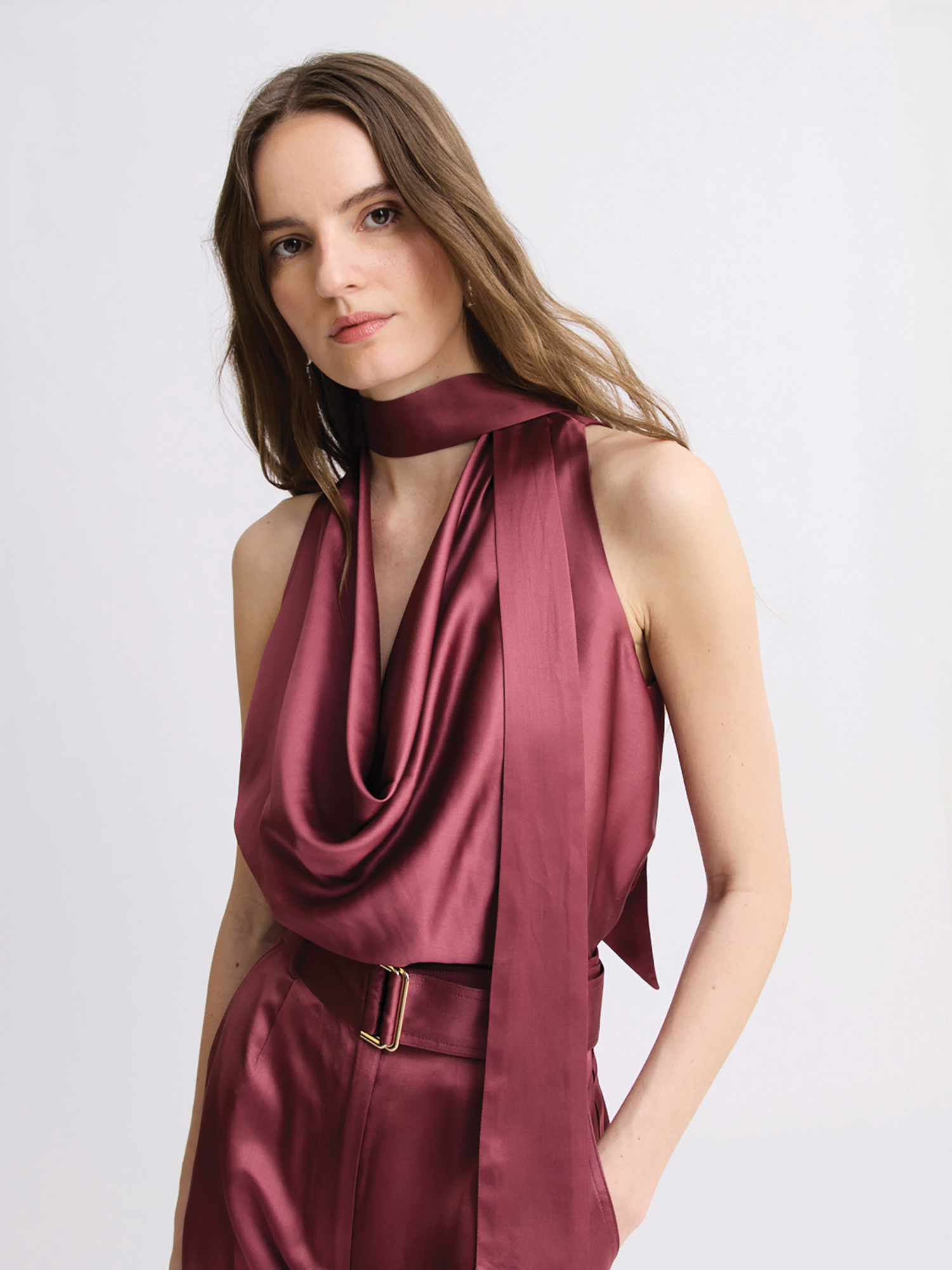 A woman modeling a sleeveless satin cowl-neck top and matching high-waisted trousers in a merlot color, set against a plain light gray studio background.

Matthew Bruch- Cowl Scarf Tank Top - Merlot Satin. Available at Edit by Elaine Turner in Houston, TX. Front Model View. 