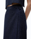 Close-up of a model wearing a dark navy blue textured skirt with a dotted studded pattern and a matching cropped top against a white background.

PINKO- Fully Rhinestoned Calf-Length Wrap Skirt in Iris Blue. Available at Edit by Elaine Turner in Houston, TX. Model Close Up view. 