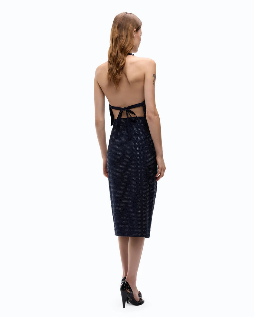 A woman shown from the back wearing a dark navy midi dress with a textured pattern, cutout back, and black high heels against a plain white background.

PINKO- Fully Rhinestoned Calf-Length Wrap Skirt in Iris Blue. Available at Edit by Elaine Turner in Houston, TX. Full back model view. 