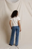A model viewed from behind wearing blue wide-leg jeans and a cream colored top, standing against a draped cream fabric backdrop.

PerfectWhiteTee- Cleo French Terry short sleeve in Sugar. Available at Edit by Elaine Turner in Houston, TX. Full Model Back View. 