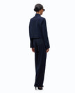 A model shown from the back wearing a dark navy blue textured jacket and matching wide-leg trousers, styled with a black beret and sunglasses against a plain white background.

PINKO Cropped Jacket with Rhinestones. Available at Edit by Elaine Turner in Houston, TX. Full back model view. 