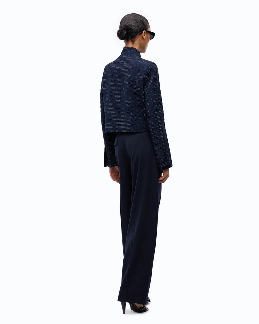 A model shown from the back wearing a dark navy blue textured jacket and matching wide-leg trousers, styled with a black beret and sunglasses against a plain white background.

PINKO Cropped Jacket with Rhinestones. Available at Edit by Elaine Turner in Houston, TX. Full back model view. 