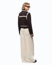 A model shown from the back wearing a brown cropped knit cardigan with white stripes, paired with cream wide-leg trousers and black sunglasses, against a plain white background.

Pinko New Sulcis Giacca. Available at Edit by Elaine Turner in Houston, TX Full model back view. 