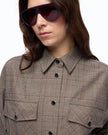 A close-up of a model wearing oversized dark sunglasses and a beige/bordeaux/black plaid button-up shirt with chest pockets, set against a plain white background.

Pinko Oncidium Overshirt Misto Lana in beige/bordeaux/black. Available at Edit by Elaine Turner in Houston, TX. Model Close up View. 