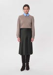 A model stands against a light gray studio background wearing a taupe knit sweater over a light blue collared shirt, paired with a dark olive green midi skirt, dark brown tights, and dark brown knee-high boots.

Tara Jarmon- Julia Skirt in Kaki. Available at Edit by Elaine Turner in Houston, TX. Model front view. 