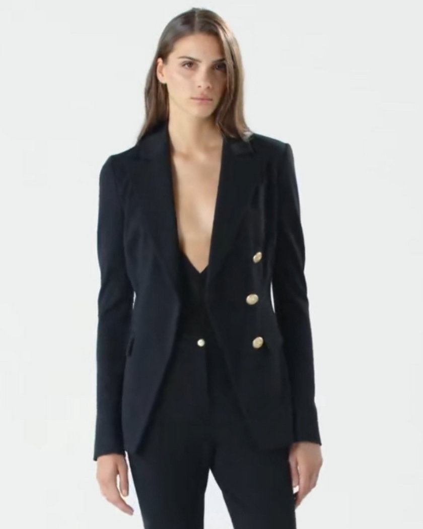 Woman wearing a black blazer with gold buttons on a white background BY PINKO