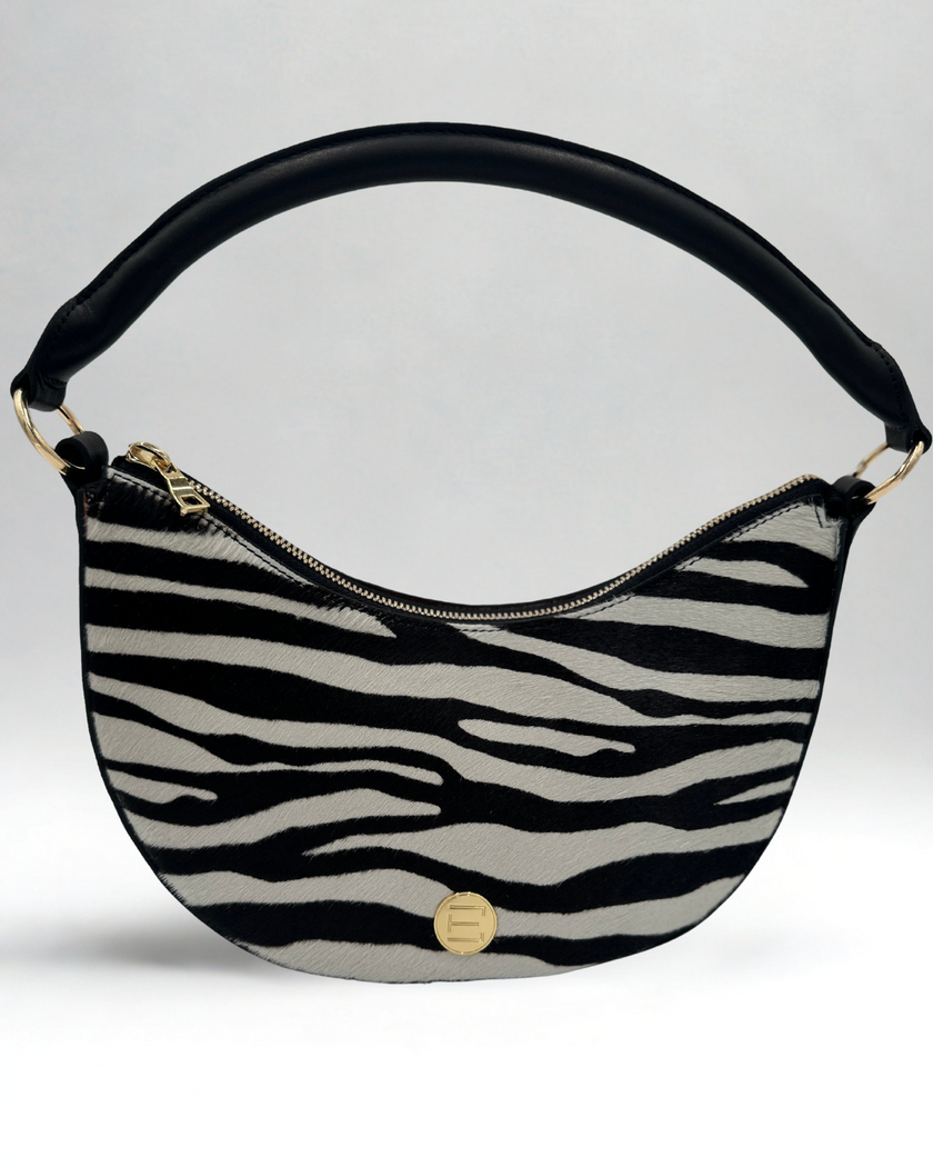 Elaine Turner Crescent Shoulder Handbag with zebra pattern and black handle on a light gray background. Comes with detachable shoulder strap.
